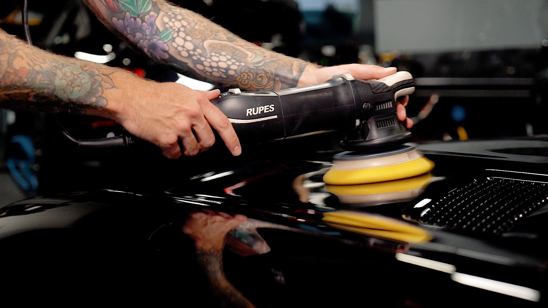 close up of worker using a tool to apply ceramic coating to a car